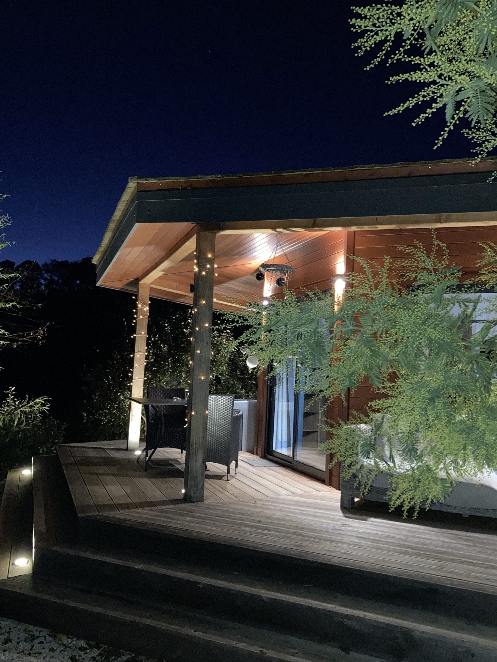 féérie des lumières à cabane du potager Cabane en bois lumineuse à Languedoc-Roussillon, avec terrasse accueillante.