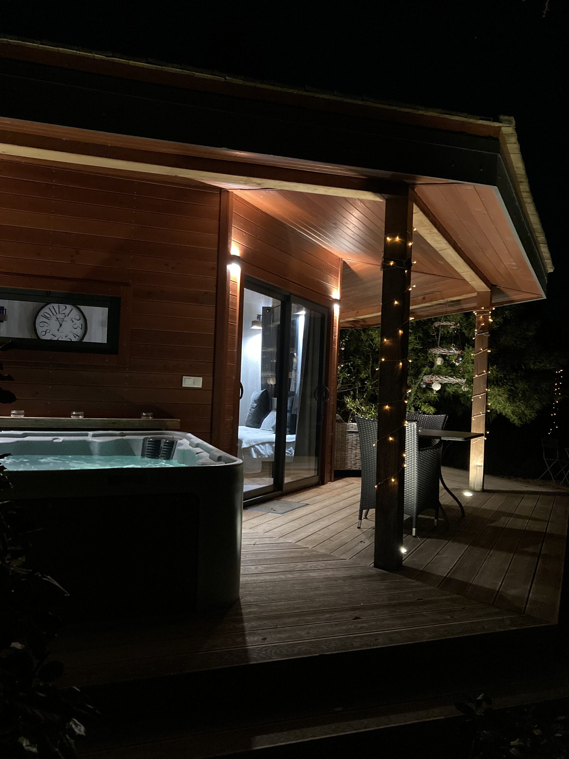 nuit étoilée sur la terrasse -cabane du potager Hébergement insolite en bois avec jacuzzi, illuminé par des guirlandes lumineuses.