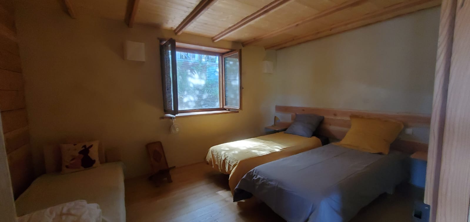 IMG-20240410-WA0004 Chalet en bois lumineux avec lits simples et fenêtres ouvertes sur la nature.