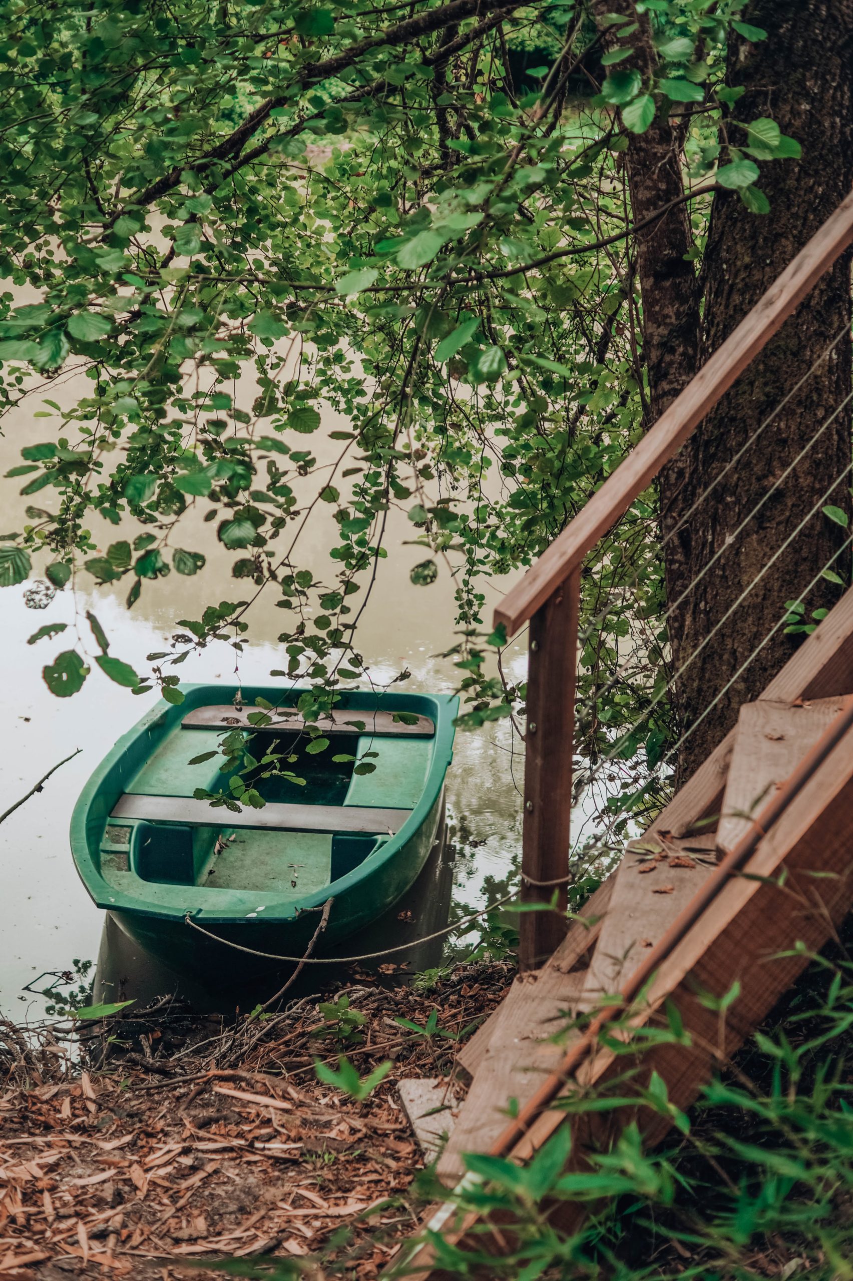 barque Hébergement insolite en Nouvelle-Aquitaine, bateau vert amarré près dun arbre.