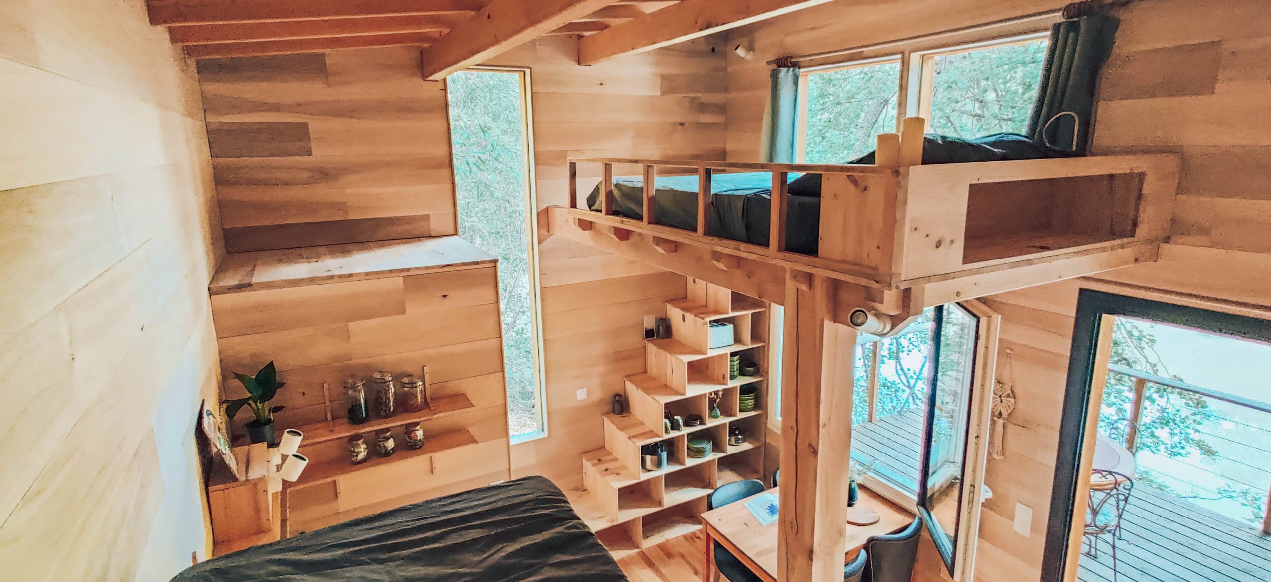 interior Cabane en bois avec mezzanine, grandes fenêtres offrant une vue sur la nature.