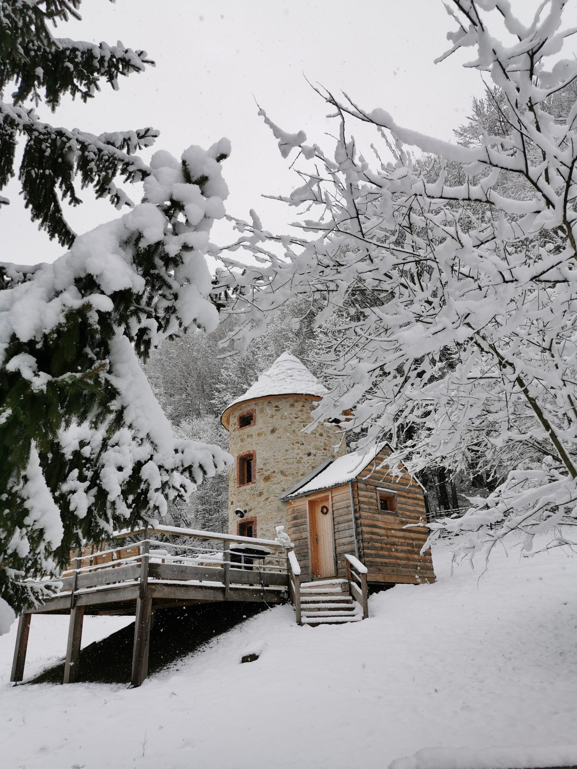 IMG_20210105_104708 Cabane en bois en forme de tour, entourée de neige et de sapins majestueux.