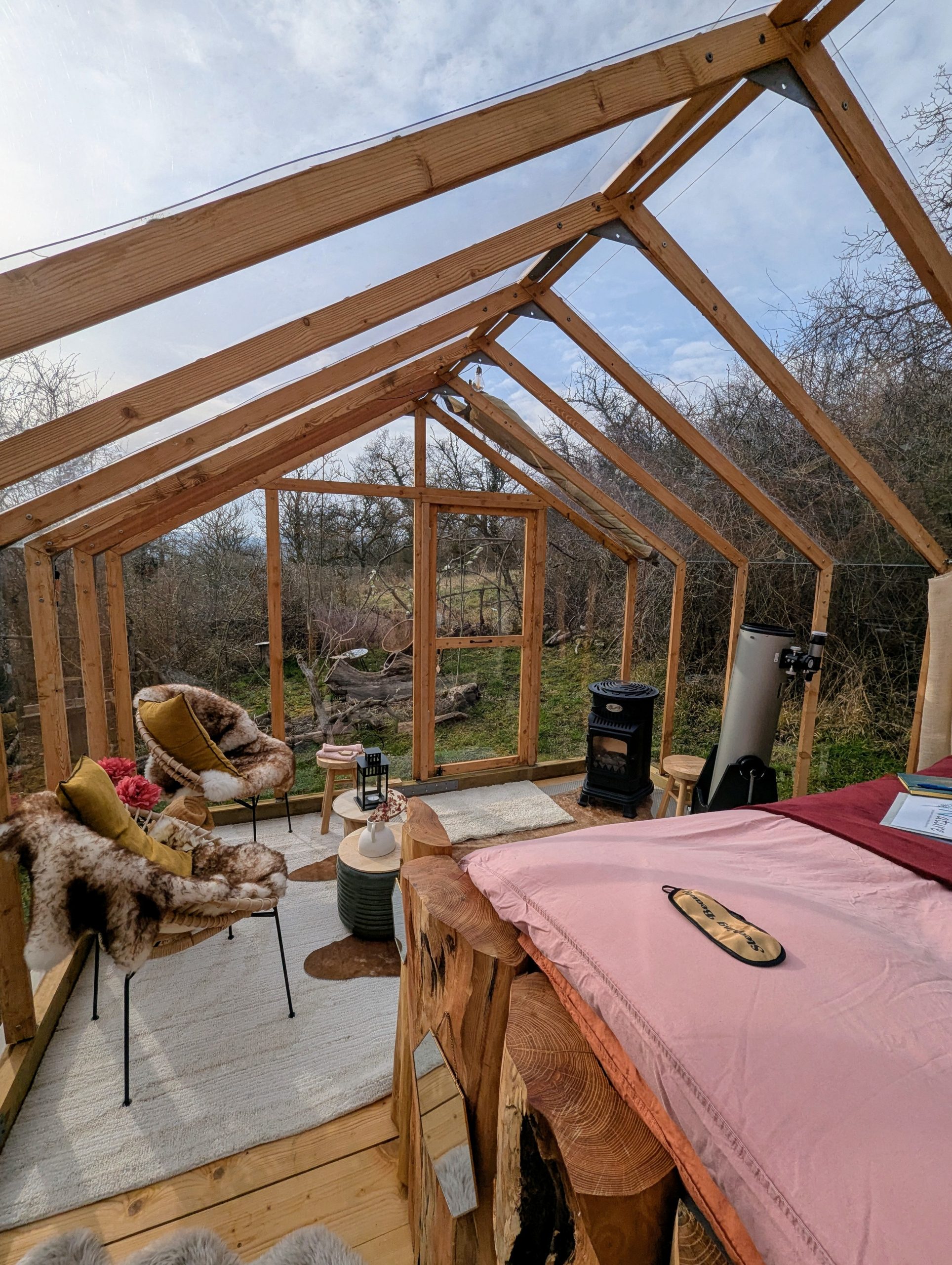 PXL_20250208_124500018~2 Cabane en bois avec vue sur la nature, fauteuils confortables et poêle à bois.