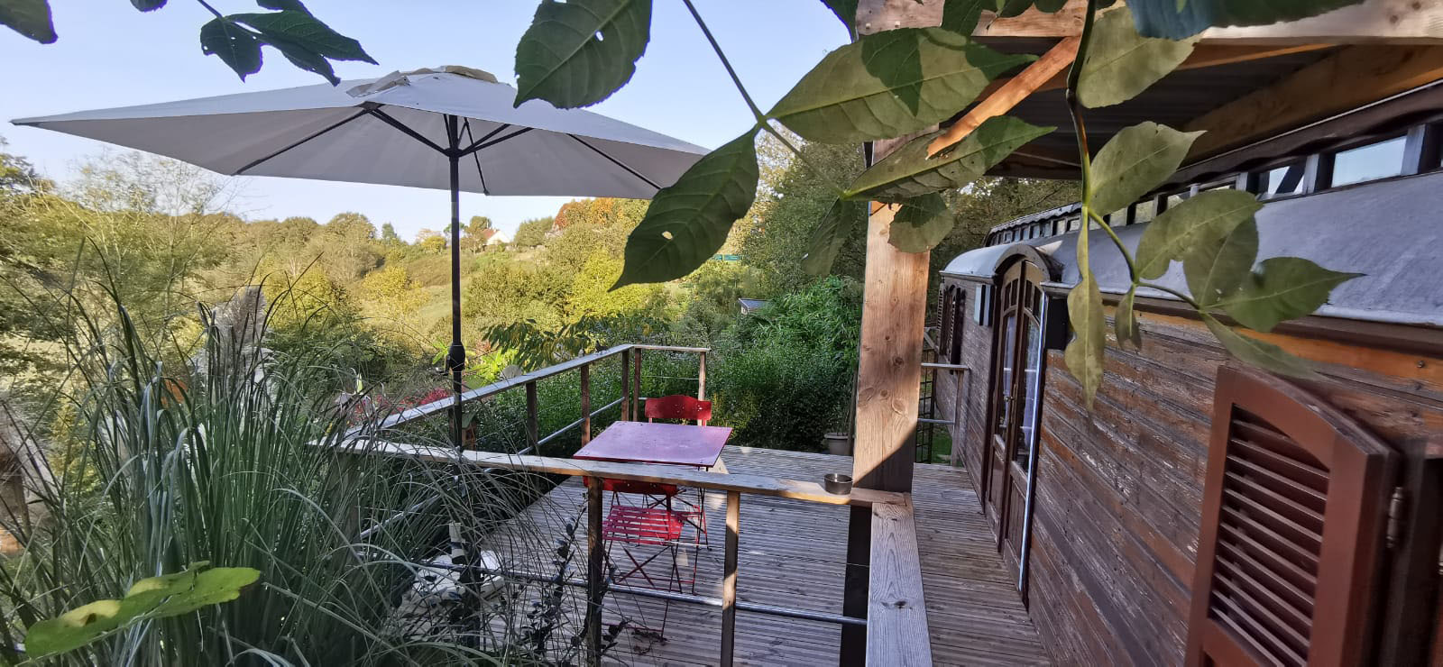 Terrasse roulotte Cabane en bois avec terrasse, parasol et vue sur la nature en Aquitaine.