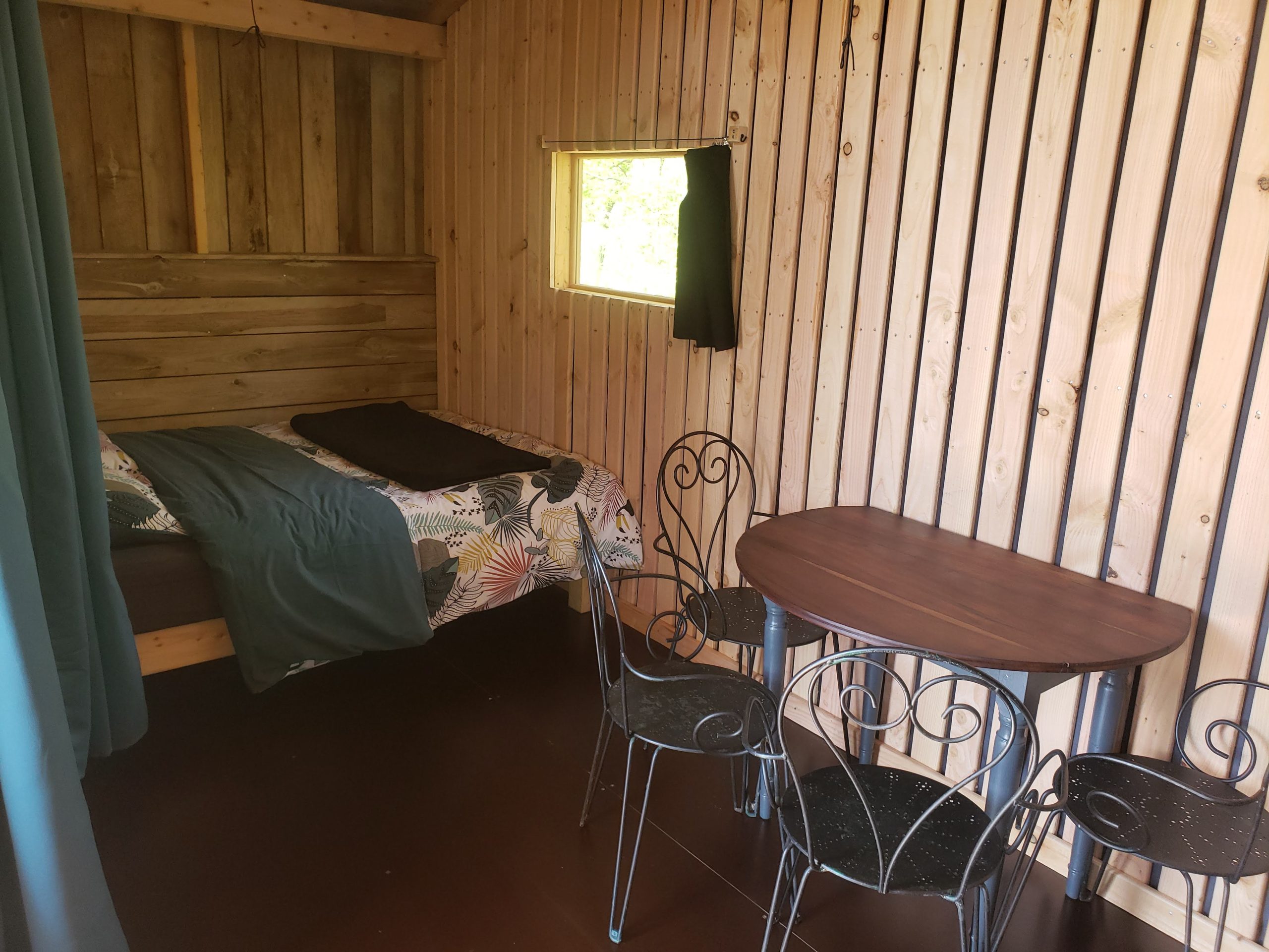 20250410_122507 Cabane en bois à Haute-Normandie avec lit douillet et table en fer forgé.