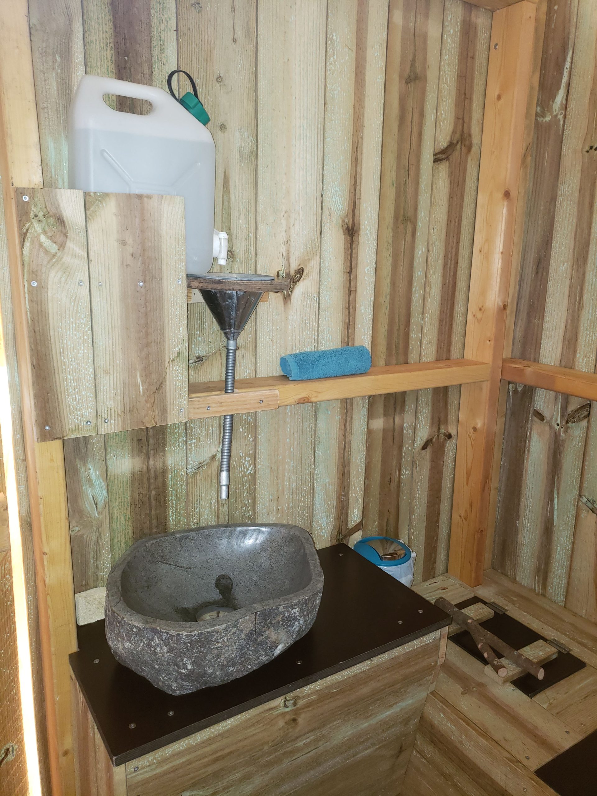 20250410_122608 Cabane en bois avec lavabo en pierre, ambiance rustique et naturelle.