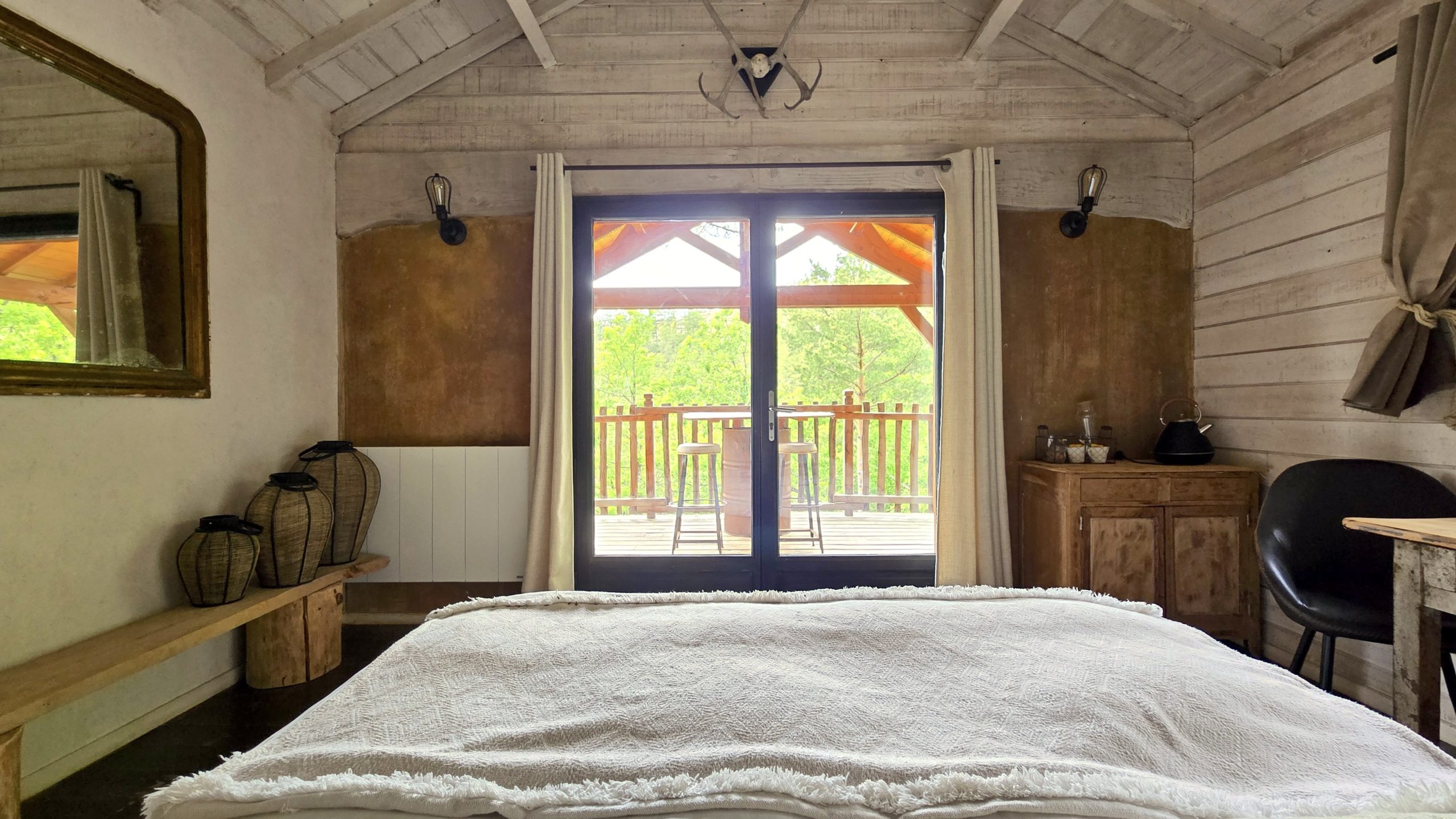20250519_163102 2 Chalet en bois avec vue sur la nature, lit douillet et terrasse ensoleillée.