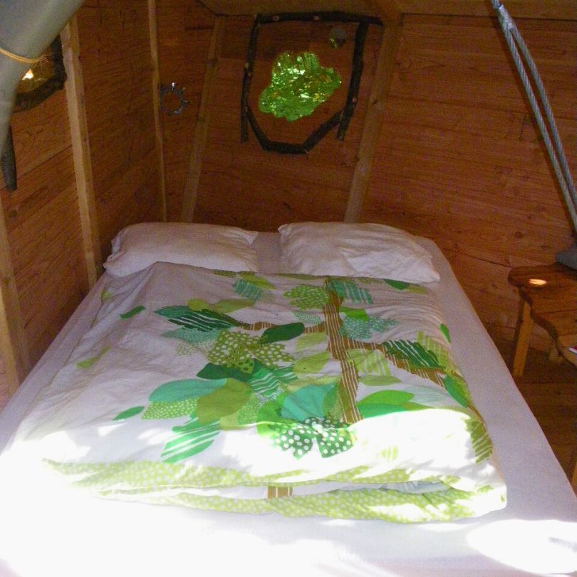 Berceau1 Chambre dans un hébergement en bois, décorée de motifs végétaux et lumineuse grâce à une fenêtre.