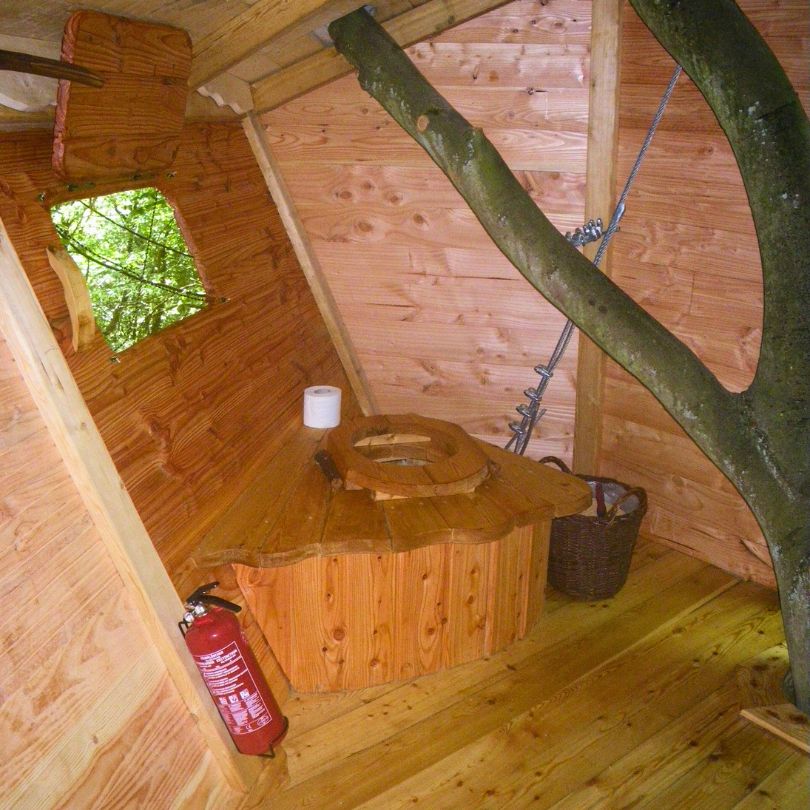 Berceau2 Cabane dans les arbres avec un intérieur en bois, incluant un coin toilette original.