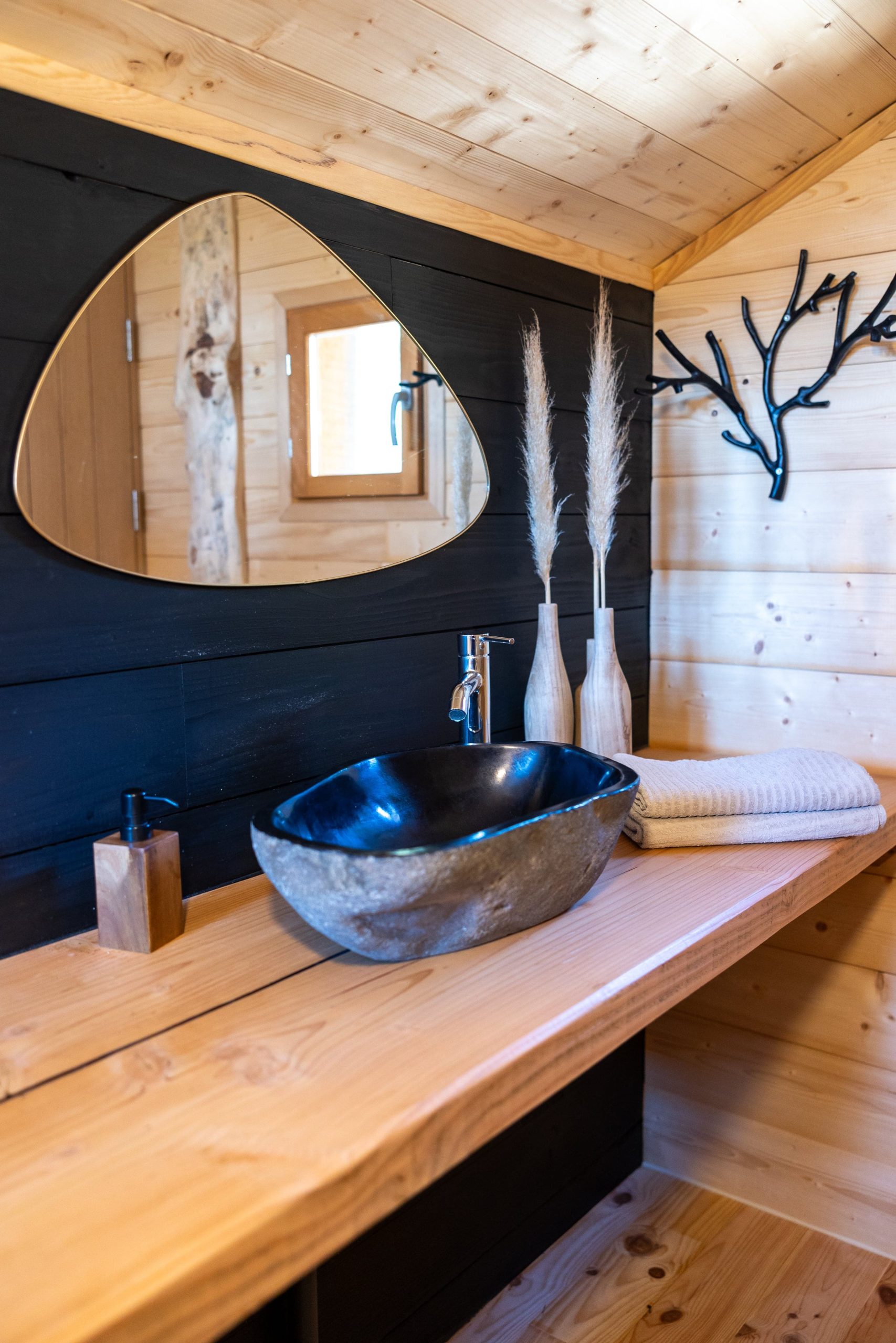 Copie de Version web-6 Salle de bain dun hébergement insolite en bois, avec lavabo en pierre et décor naturel.