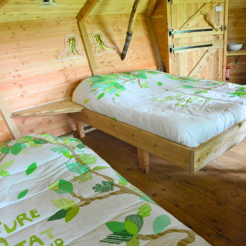 Drakkar3 Chalet en bois avec lits confortables, décoré de motifs végétaux apaisants.