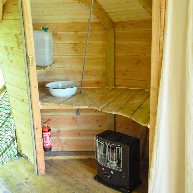 Drakkar4 Intérieur d'une cabane en bois avec un lavabo, un poêle et des murs en bois naturel.