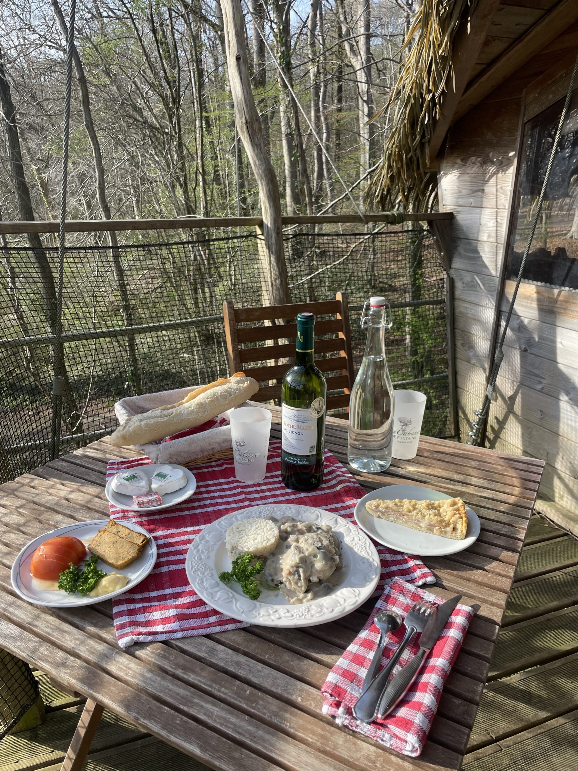 IMG_1469 Repas savoureux sur la terrasse d'une cabane dans les arbres, entourée de verdure.