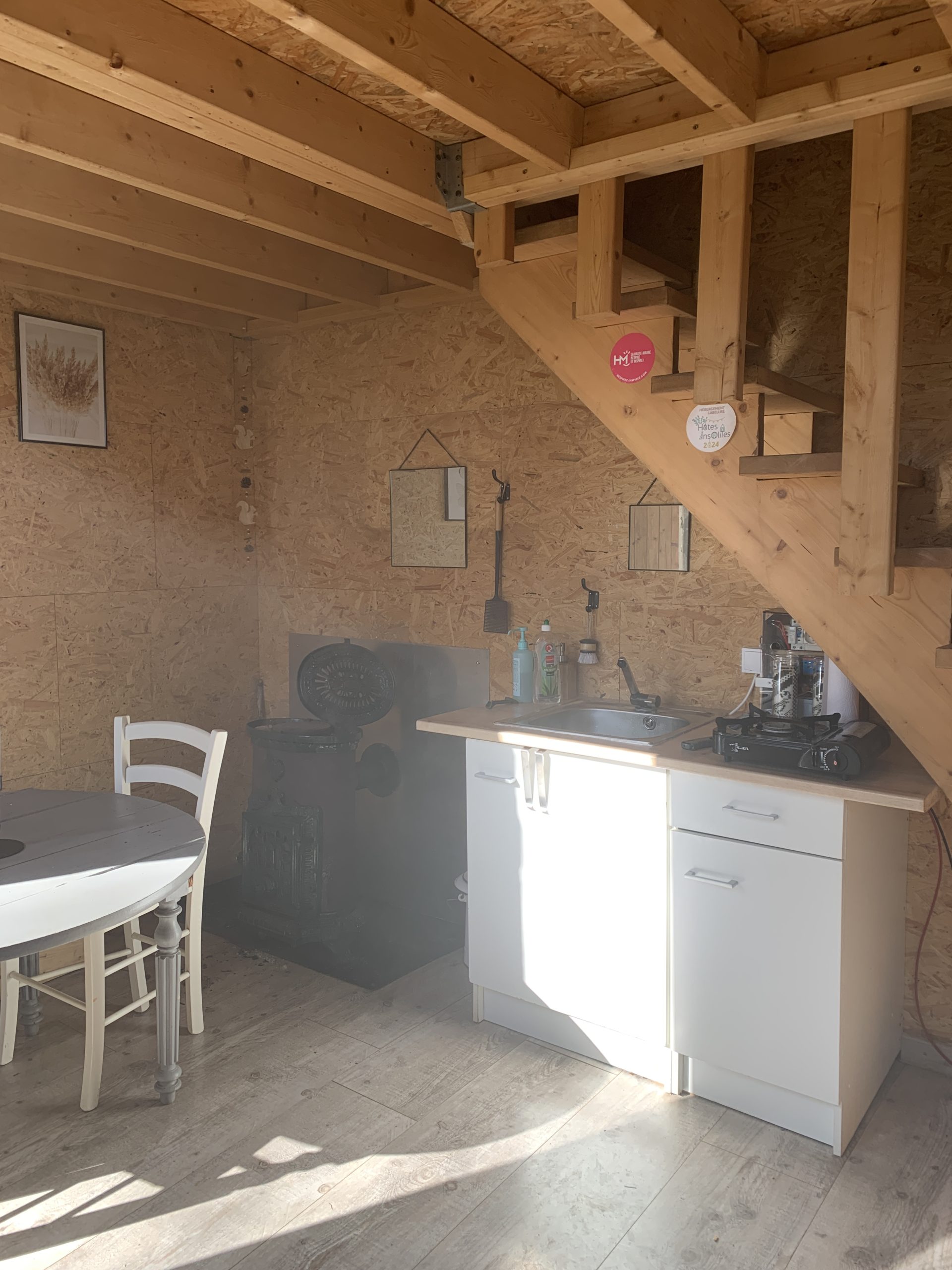IMG_2627 Cabane en bois avec cuisine équipée, poêle à bois et coin repas lumineux.