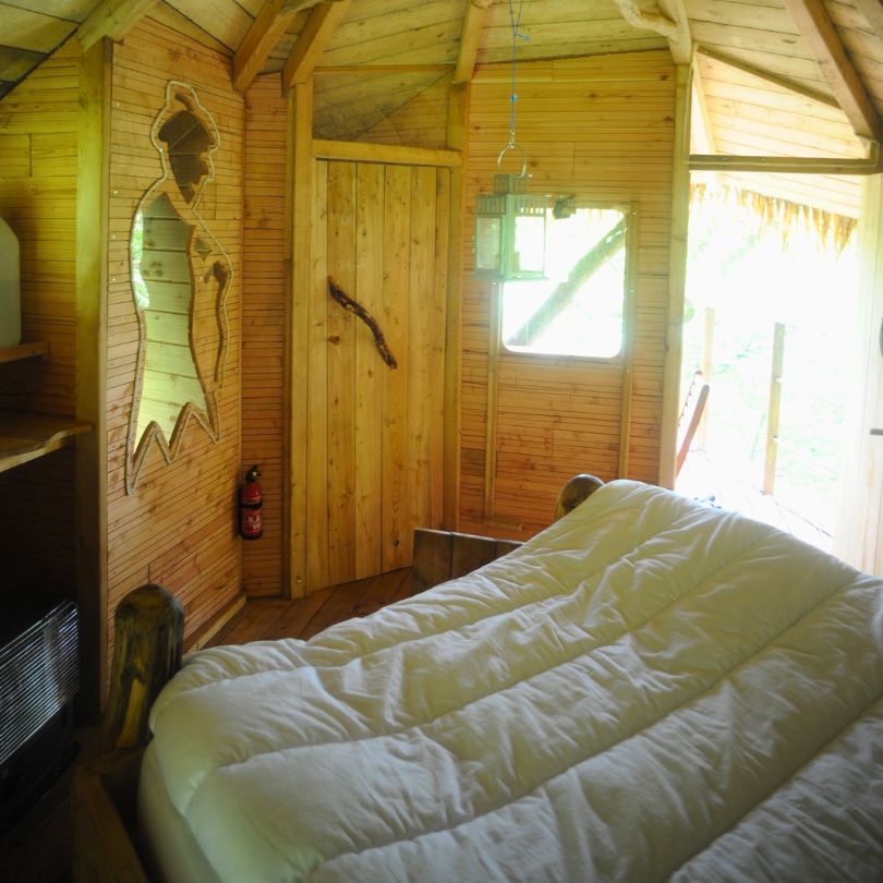 Vieux chène3 Cabane en bois avec intérieur chaleureux, lit douillet et décor en bois naturel.