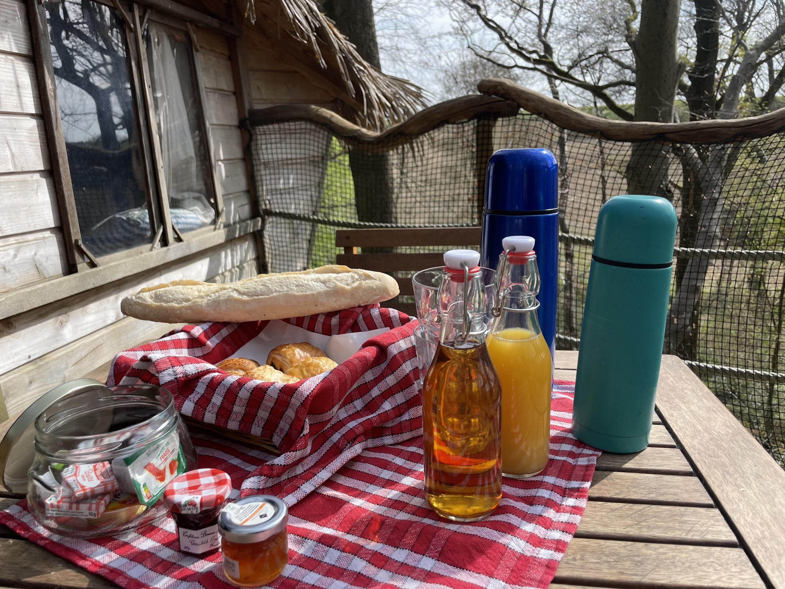 pti dej Cabane perchée dans les arbres, avec un petit déjeuner gourmand sur une table en bois.