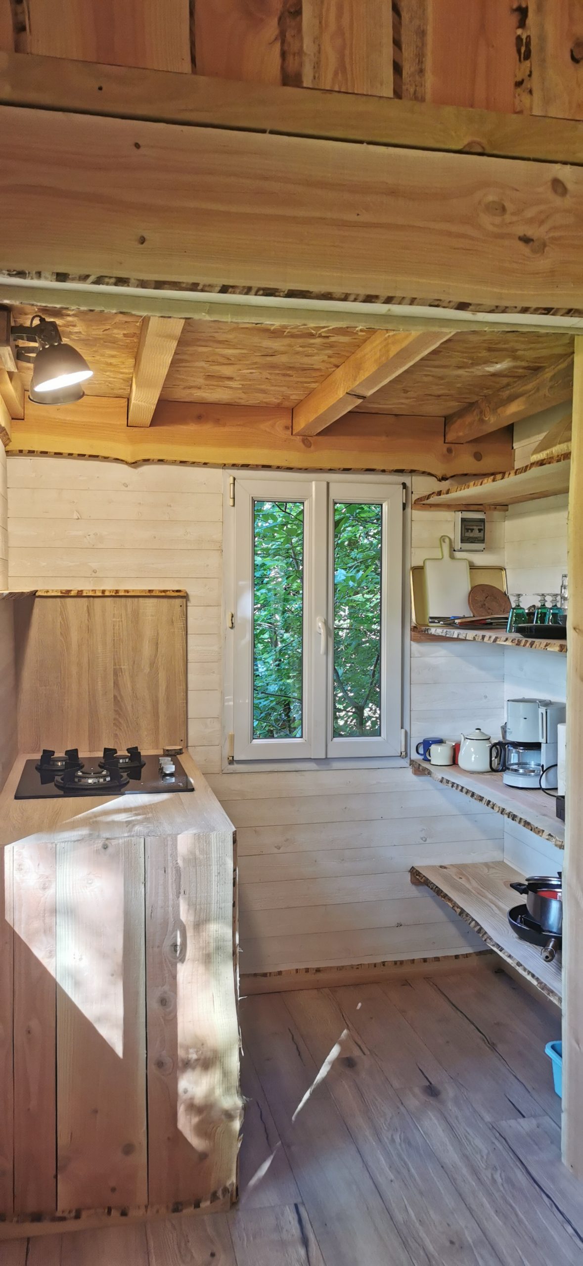 5 Intérieur d'une cabane en bois, avec cuisine équipée et lumière naturelle. Ambiance chaleureuse.