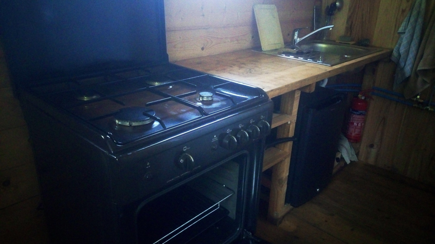 Cabane03 Cuisine rustique dans un chalet en bois, avec un four à gaz et un évier en inox.