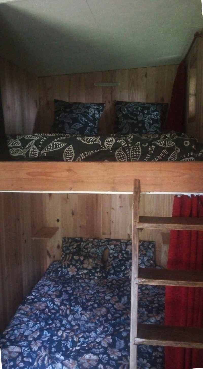 Cabane04 Cabane en bois avec lits superposés, décorée de coussins à motifs floraux. Ambiance chaleureuse.
