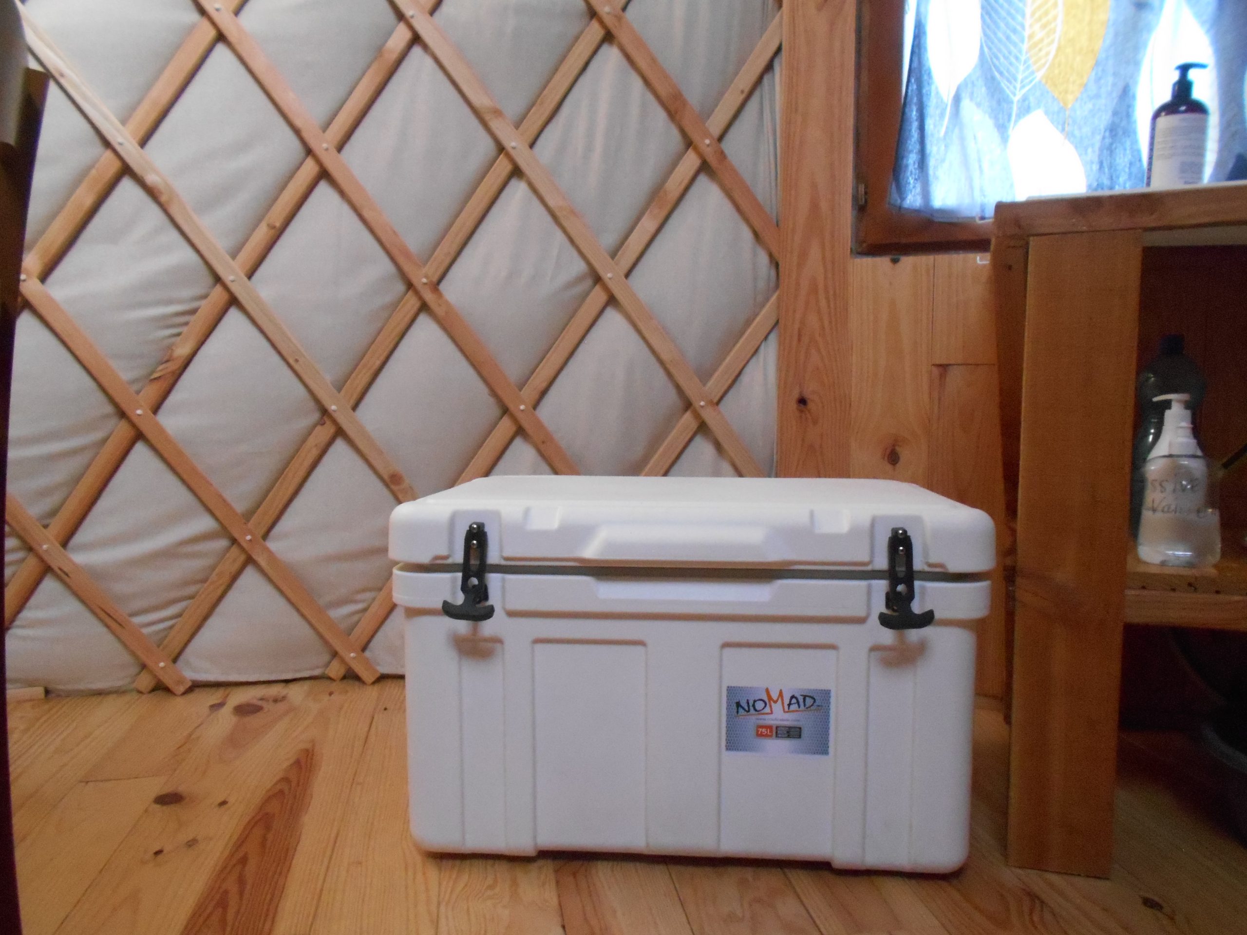 DSCN0506 Intérieur d'une yourte avec un coffre de rangement blanc sur un sol en bois.