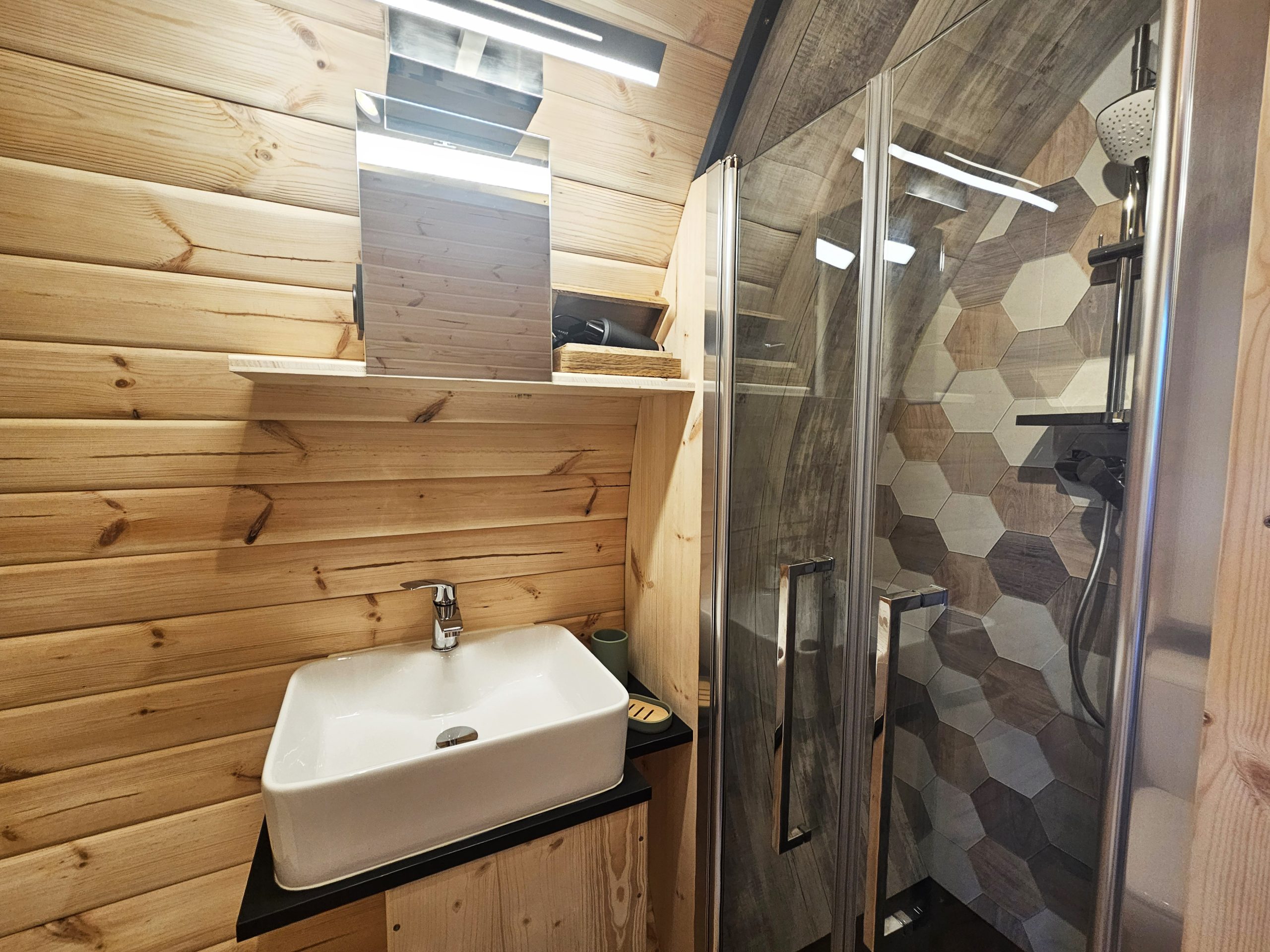 salle_d_eau_palmeraie Salle de bain moderne en bois, avec douche vitrée et lavabo design, dans un hébergement insolite.