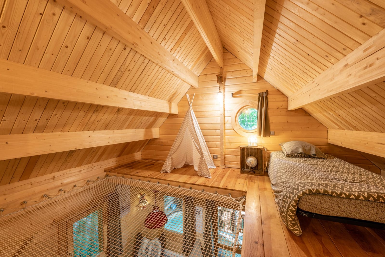 IMG-20250707-WA0017 Cabane en bois avec un intérieur chaleureux, lit douillet et filet suspendu pour se détendre.
