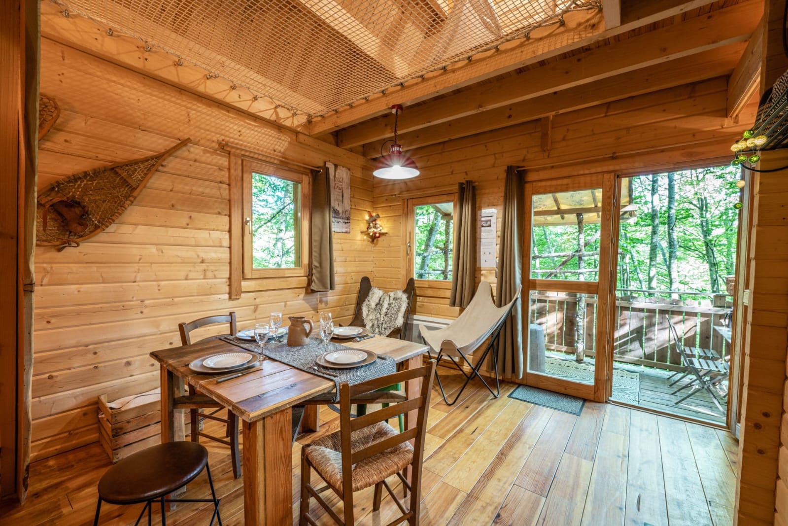 IMG-20250707-WA0020 Cabane en bois chaleureuse avec un coin repas et vue sur la nature verdoyante.