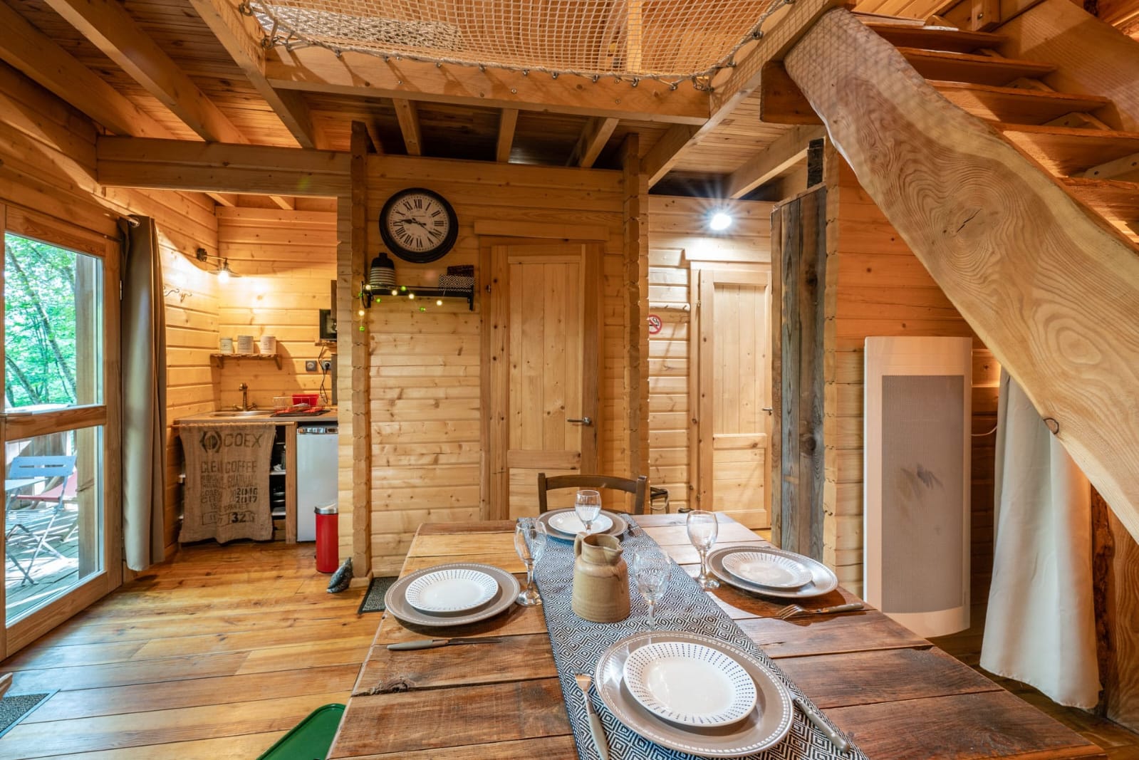 IMG-20250707-WA0021 Cabane en bois chaleureuse avec un intérieur en bois, table en bois et mezzanine.