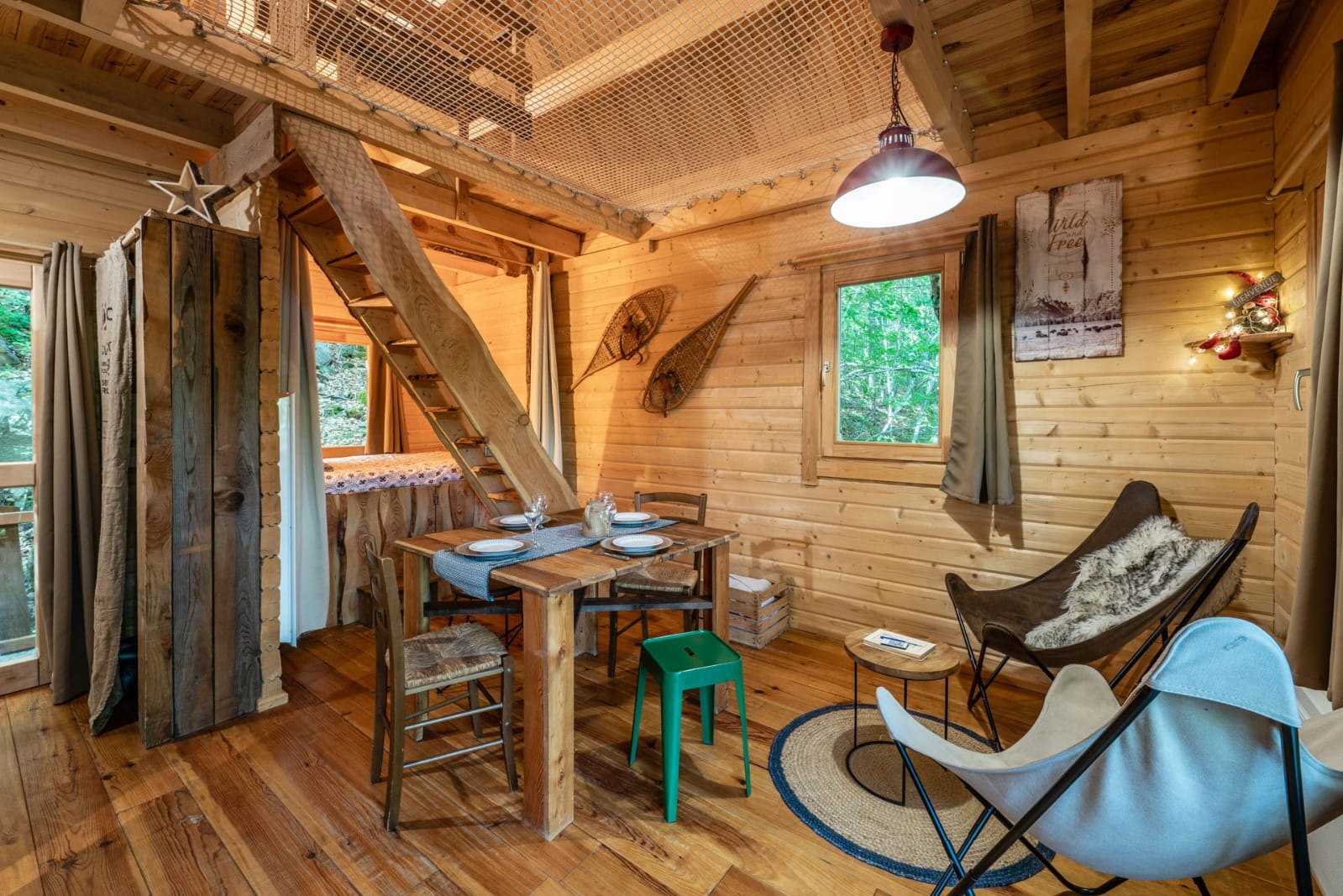 IMG-20250707-WA0022 Cabane en bois chaleureuse avec un coin repas, des escaliers en bois et une décoration rustique.