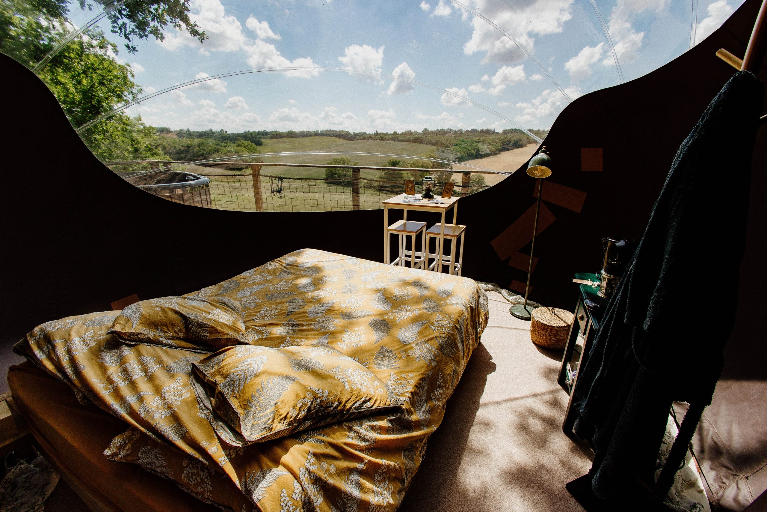 Chambre dans une bulle transparente, offrant une vue panoramique sur la nature environnante.