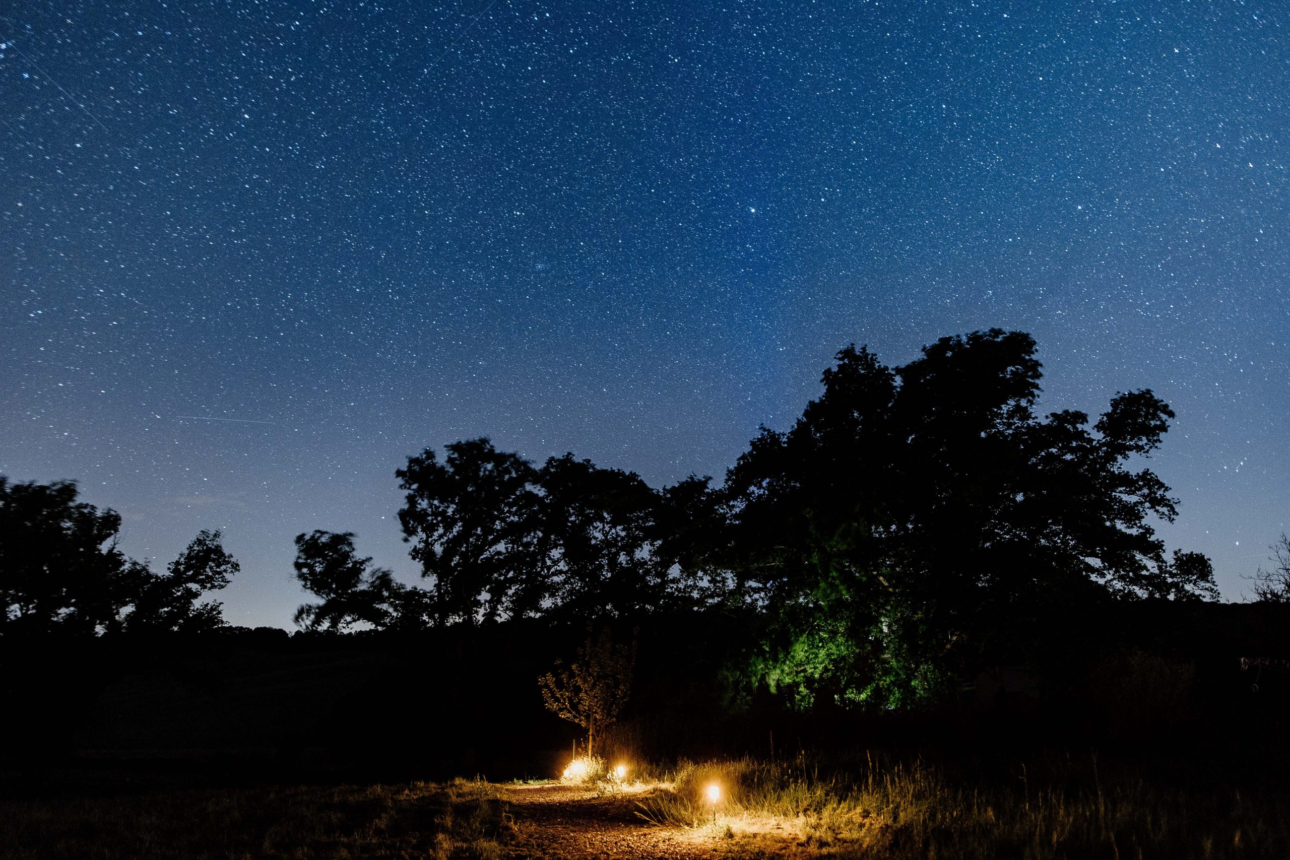 Nuit étoilée au-dessus d'un hébergement insolite, éclairé par des lanternes chaleureuses.