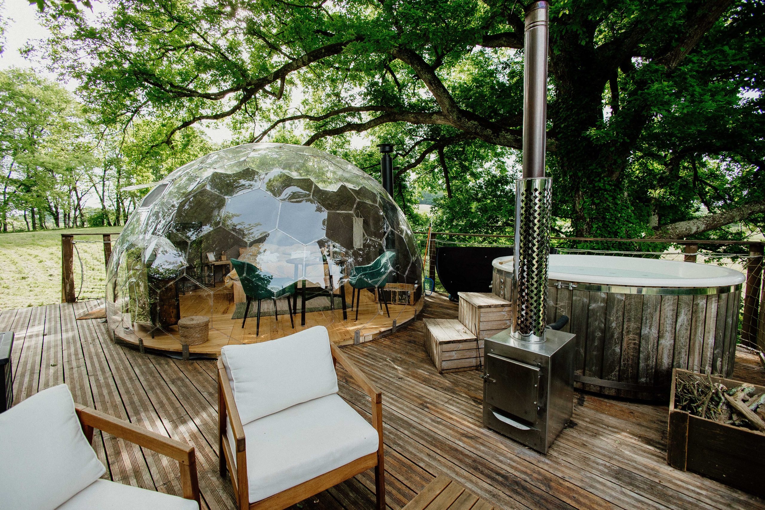 Hébergement insolite : bulle transparente en bois, jacuzzi et vue sur la nature environnante.