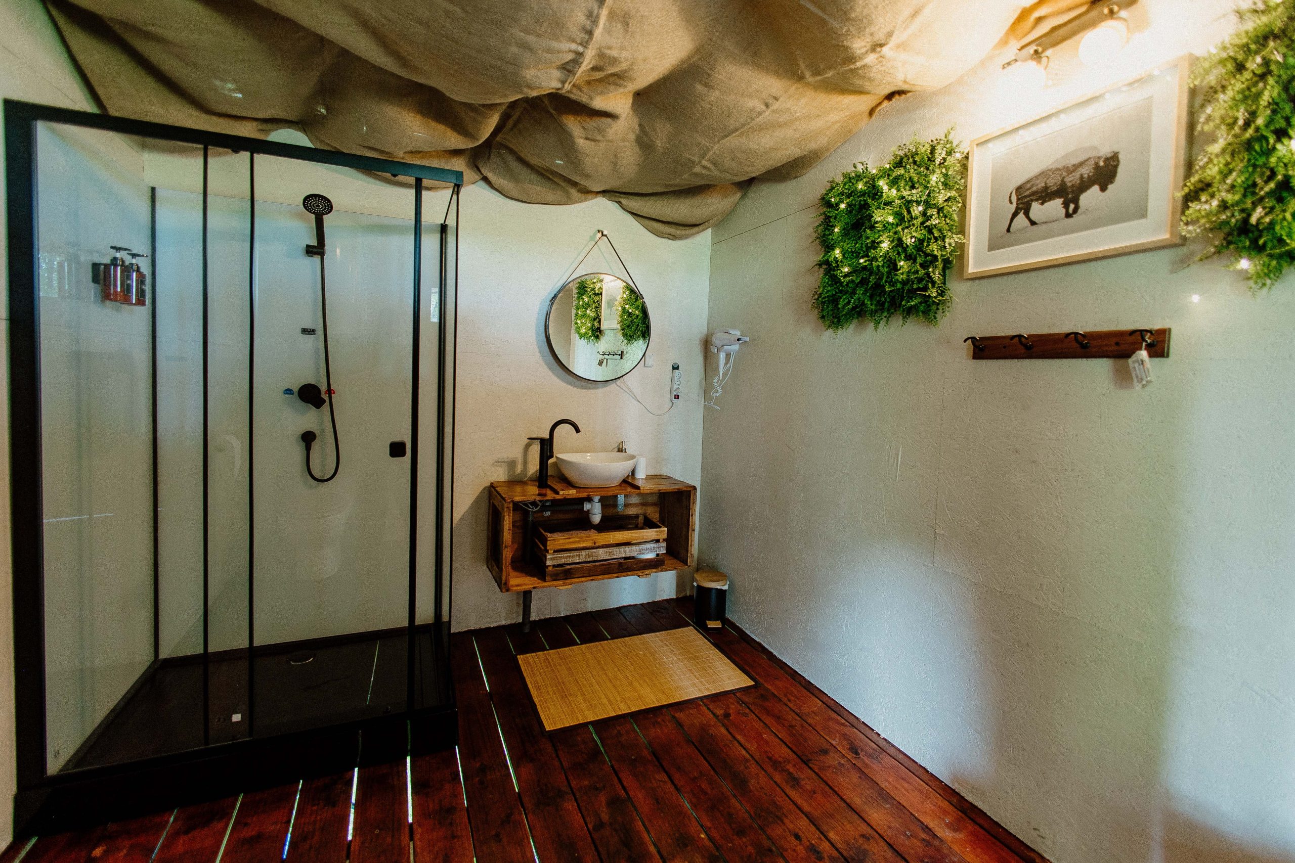 Nuit insolite_bulle_dôme_perché_occitanie_gers_Lartigue_weekend_étoiles_bain_nordique (93) Cabane moderne avec salle de bain, décorée de plantes et bois chaleureux. Ambiance cocooning.