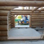 Cabane en rondins en construction, avec une vue sur l'intérieur et des murs en bois brut.