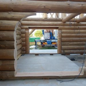 Cabane en rondins en construction, avec une vue sur l'intérieur et des murs en bois brut.
