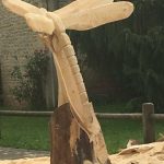 Hébergement insolite : sculpture en bois représentant une libellule, au milieu d'un jardin