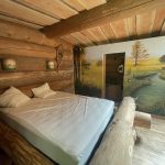 Chalet en bois avec un lit confortable et une fresque murale champêtre apaisante.