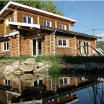 Charmante maison en bois rond, entourée d'un jardin paisible et d'un étang réfléchissant.