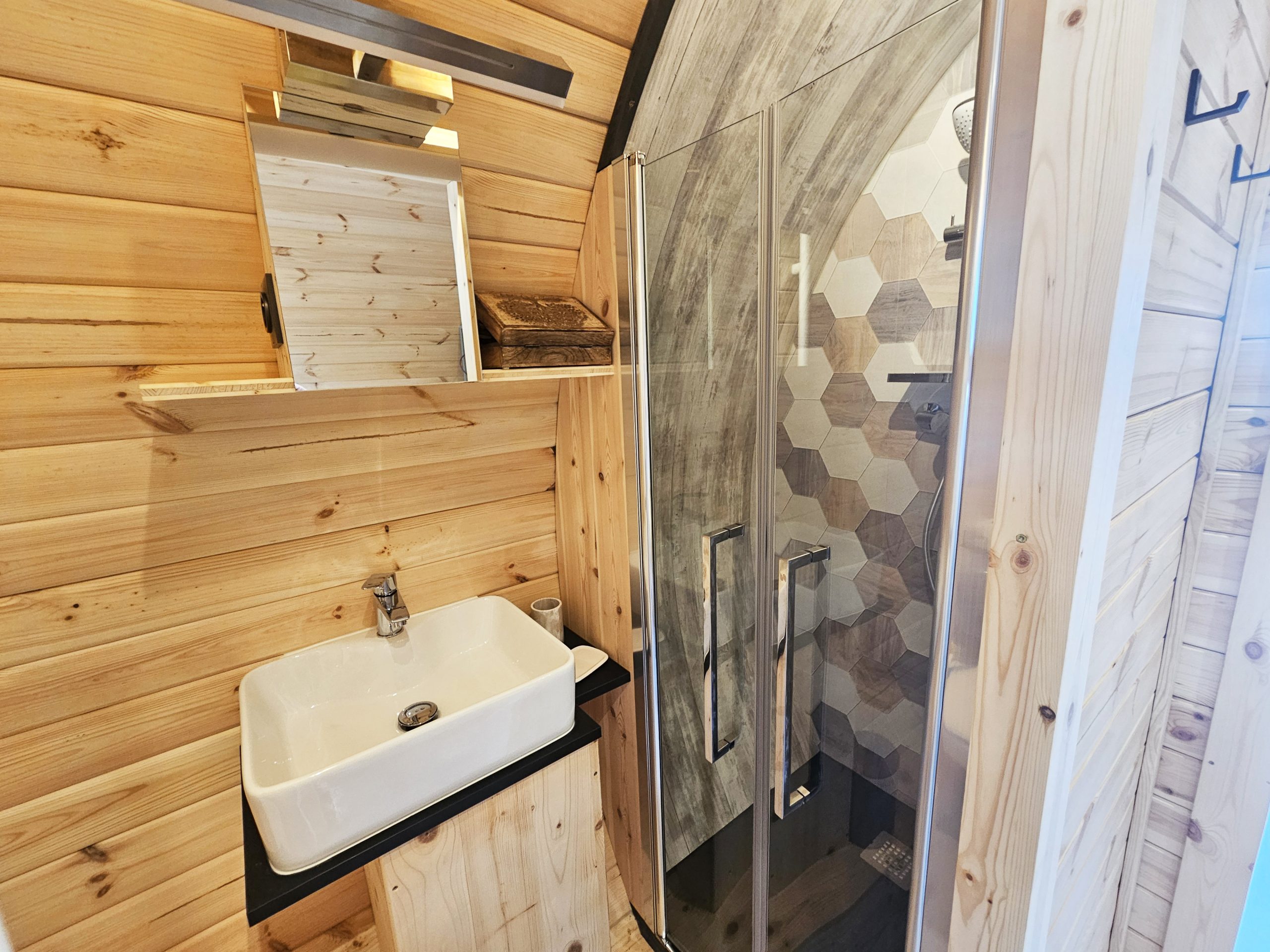 salle_d_eau Salle de bain en bois dans un hébergement insolite, avec douche à l'italienne et lavabo moderne.