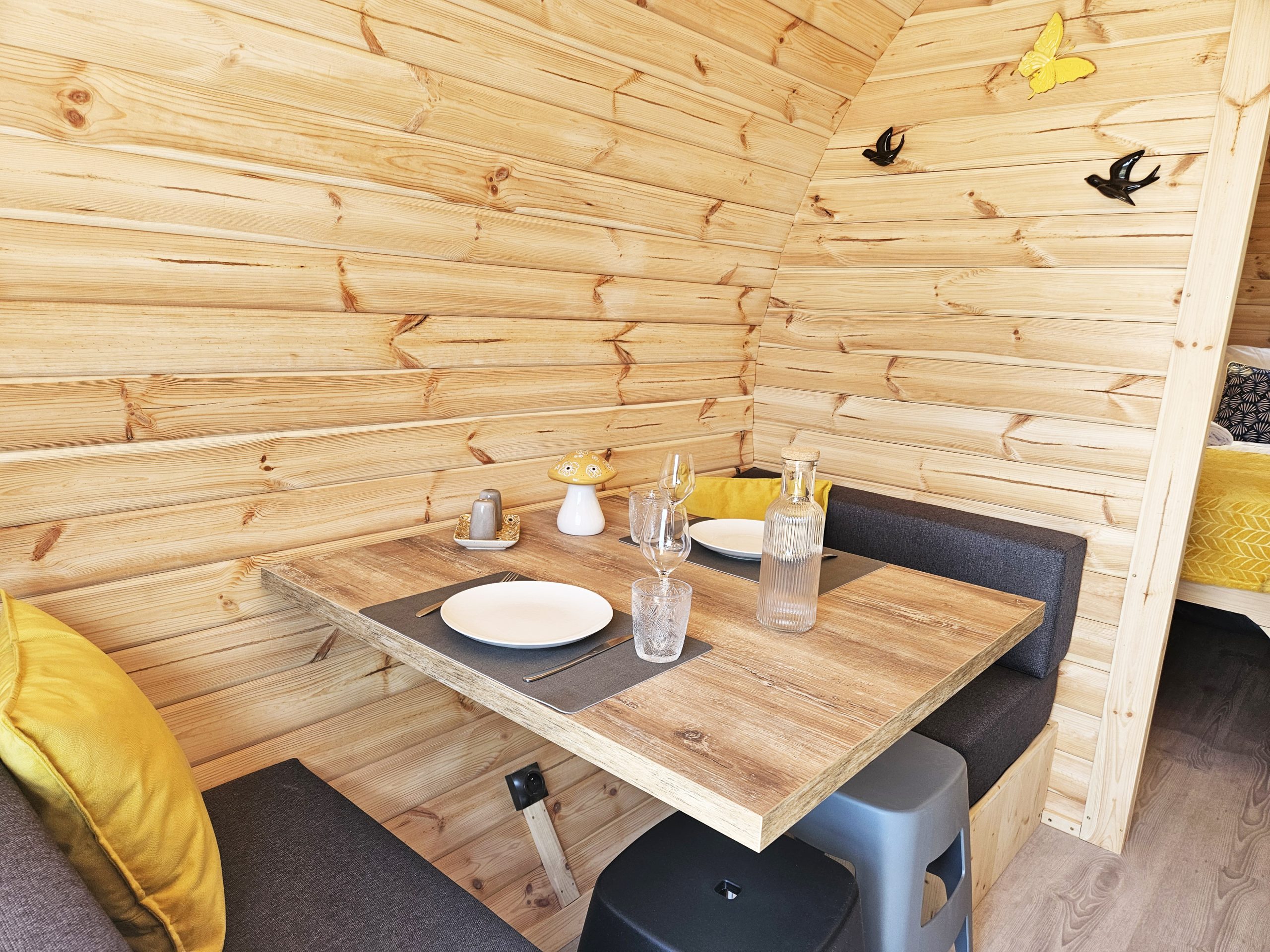 table_a_manger Intérieur d'un chalet en bois, avec une table en bois, des coussins jaunes et des décorations