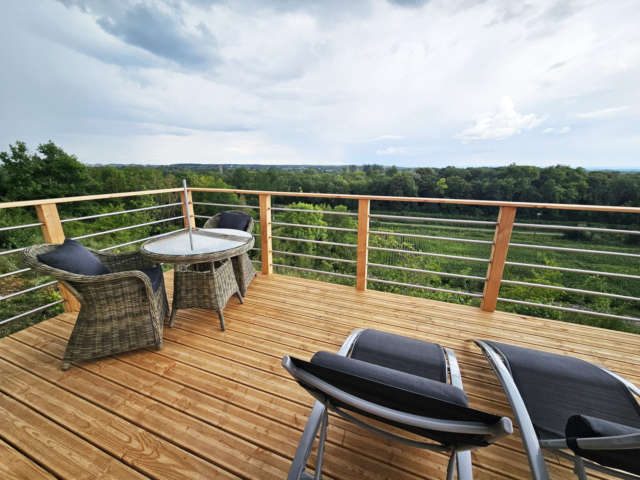 terrasse-bouton-or Terrasse en bois d'une cabane perchée, offrant une vue panoramique sur la nature environnante.