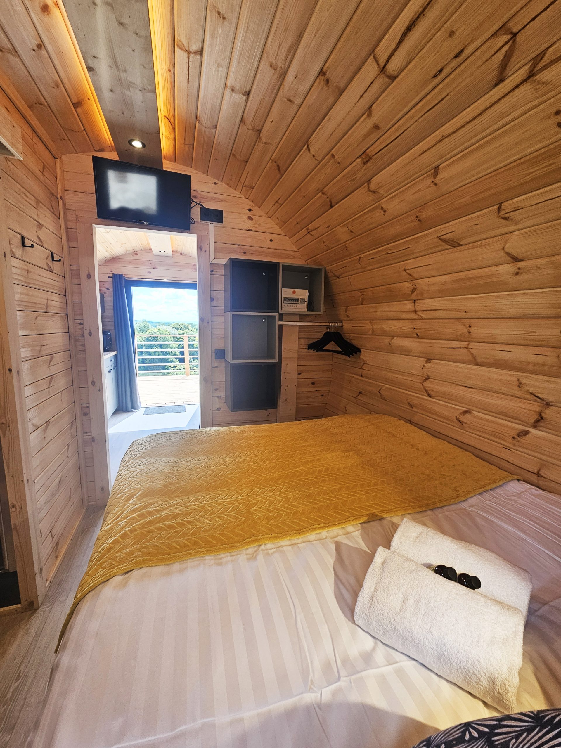 vue_depuis_chambre Intérieur d'un hébergement insolite en bois, avec lit douillet et décoration chaleureuse.