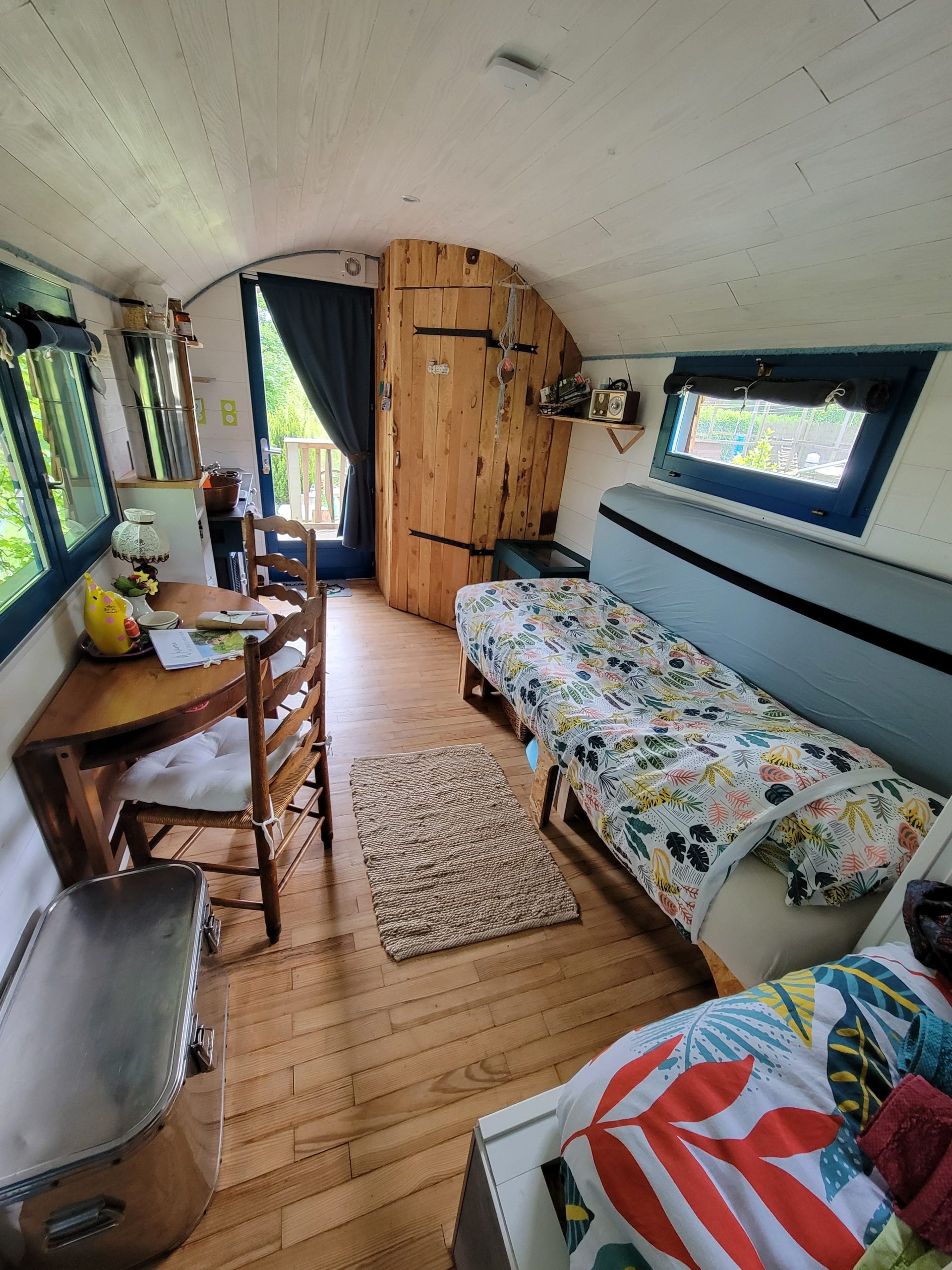 1747308417913 Intérieur d'une tiny house chaleureuse, avec un lit simple, une table en bois et des touches