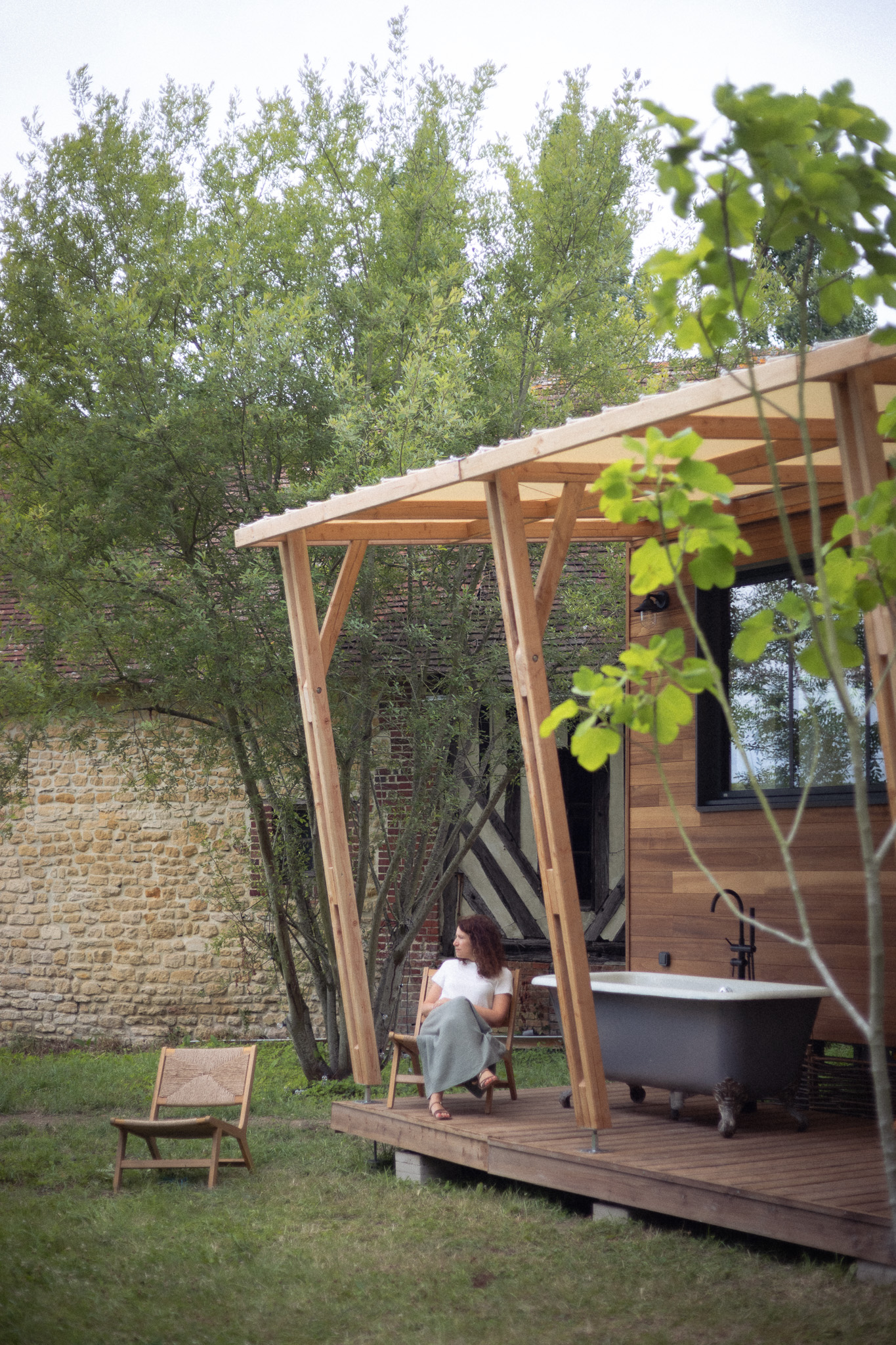 Cabane en bois avec baignoire extérieure, entourée de verdure apaisante.