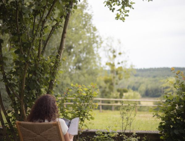Chalet en pleine nature, avec une vue dégagée sur la verdure et une personne lisant.