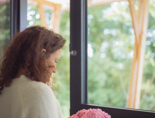 Chalet moderne avec vue sur la nature, décoré de fleurs roses sur la table.
