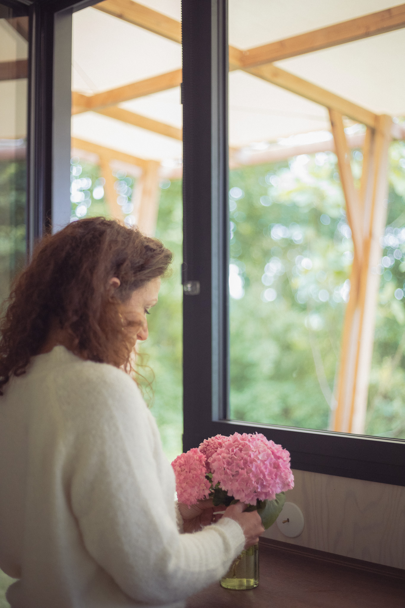 Chalet moderne avec vue sur la nature, décoré de fleurs roses sur la table.