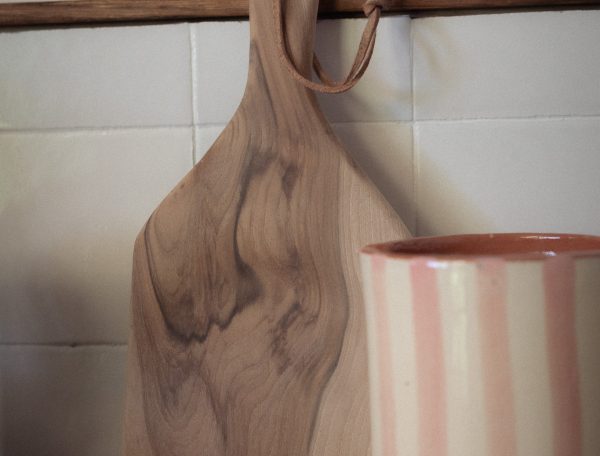 Planche en bois et tasse rayée dans un hébergement chaleureux et accueillant.