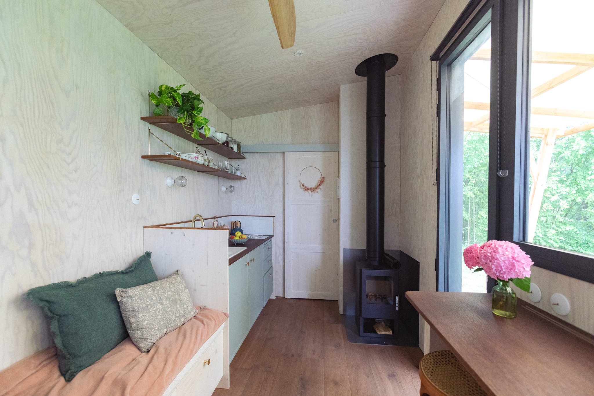 Cabane moderne avec poêle à bois et plantes, offrant un intérieur chaleureux et accueillant.