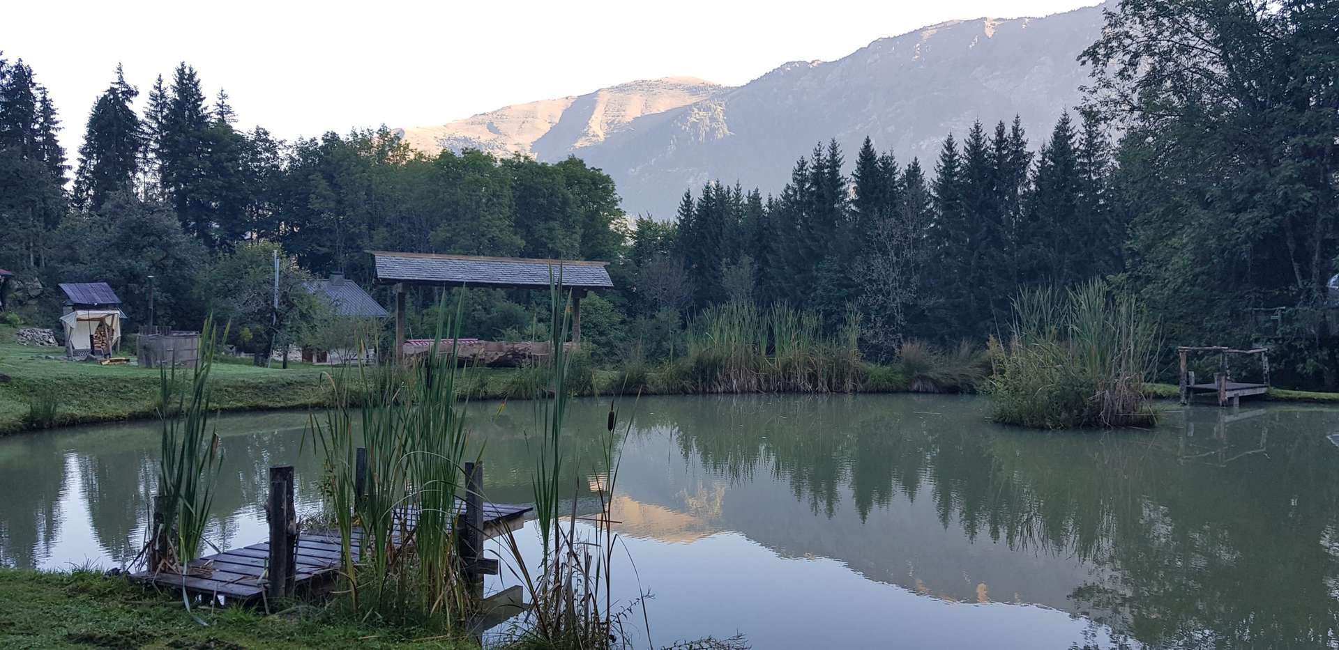 Chalet au bord dun lac, entouré de montagnes et de verdure luxuriante.